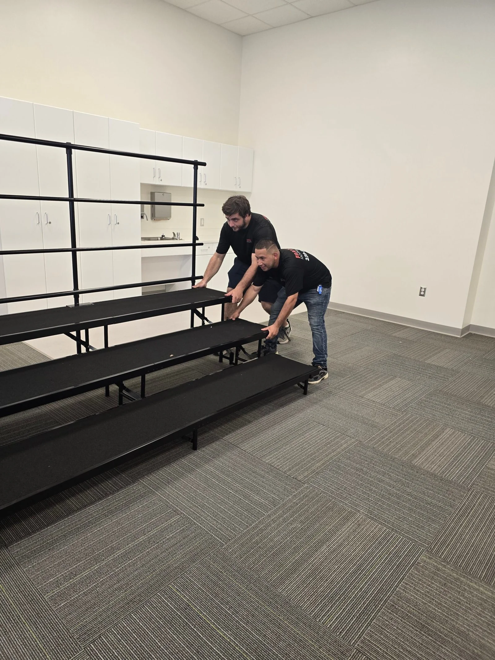 Frank and Sons movers positioning tiered risers inside a room