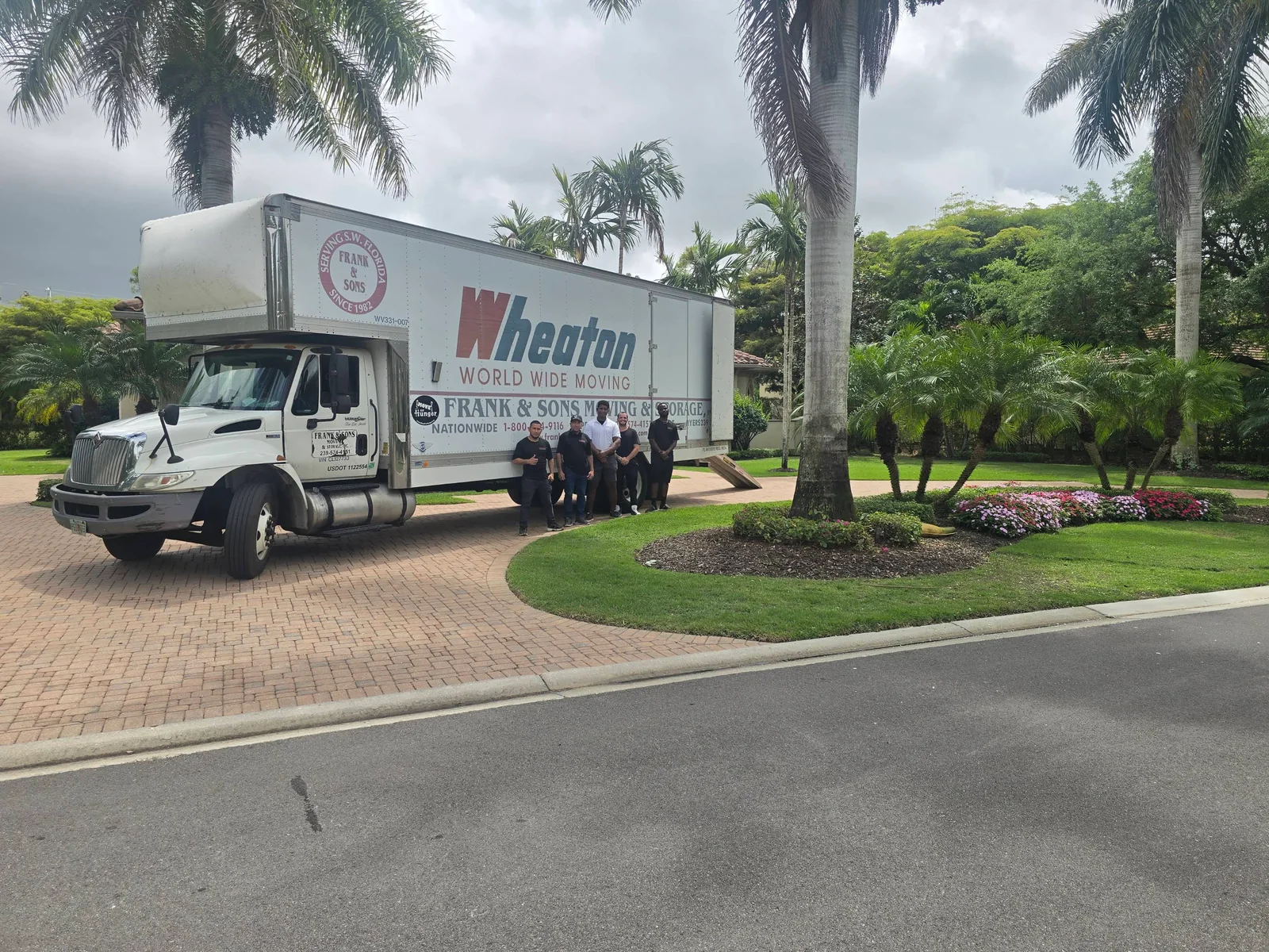 Frank and Sons moving crew and truck beside palms on a residential driveway