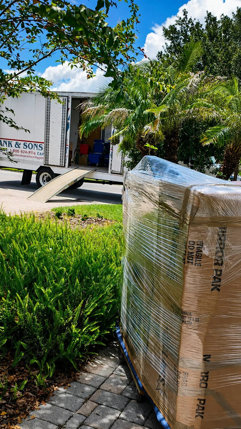 A wrapped mirror carton beside an open moving truck and loading ramp