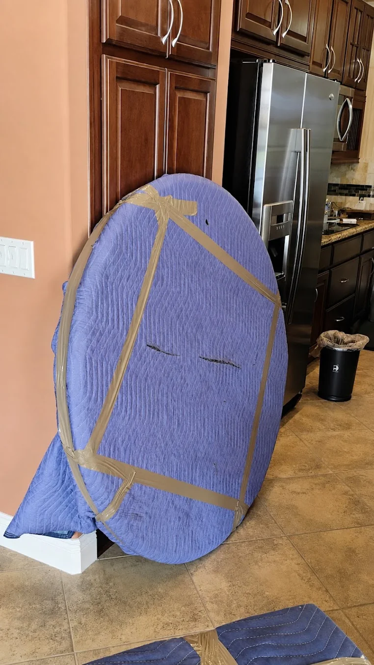 A round furniture piece carefully protected with moving blankets and straps