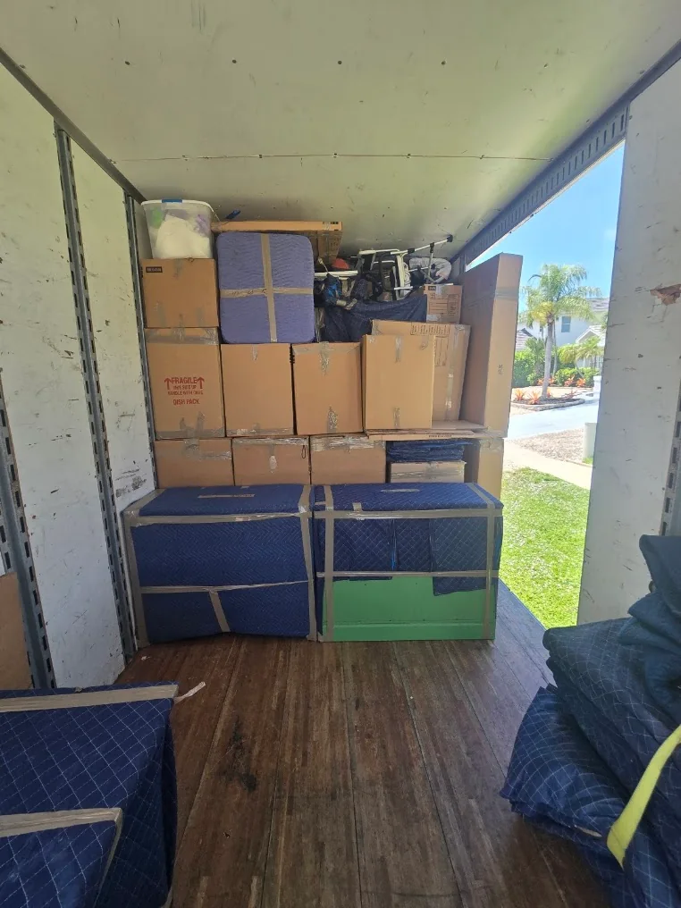Labeled cartons and padded furniture arranged inside a moving truck