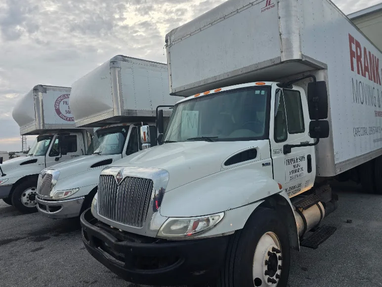 A row of Frank and Sons moving trucks outside a warehouse