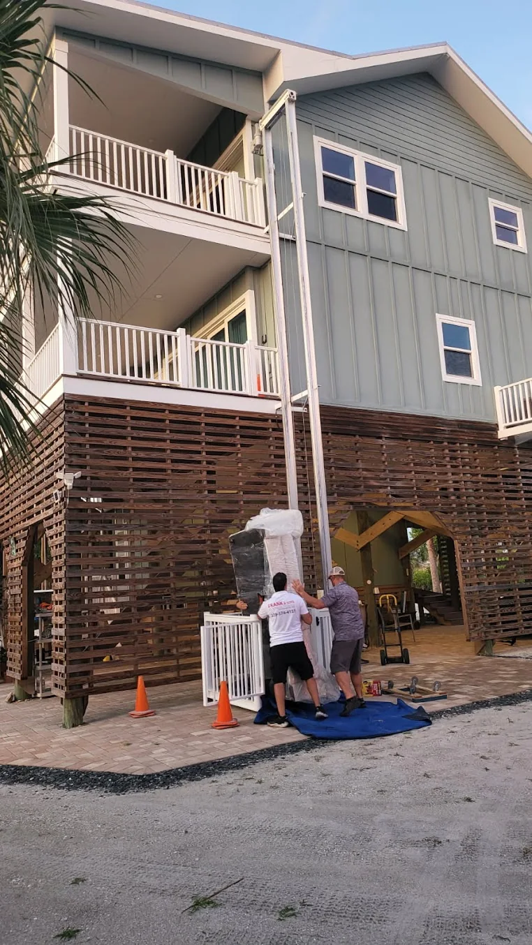 Frank and Sons movers handling a padded item outside a coastal home