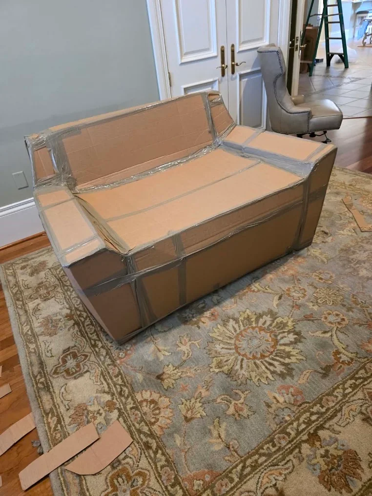 A sofa protected with cardboard and clear wrap inside a home