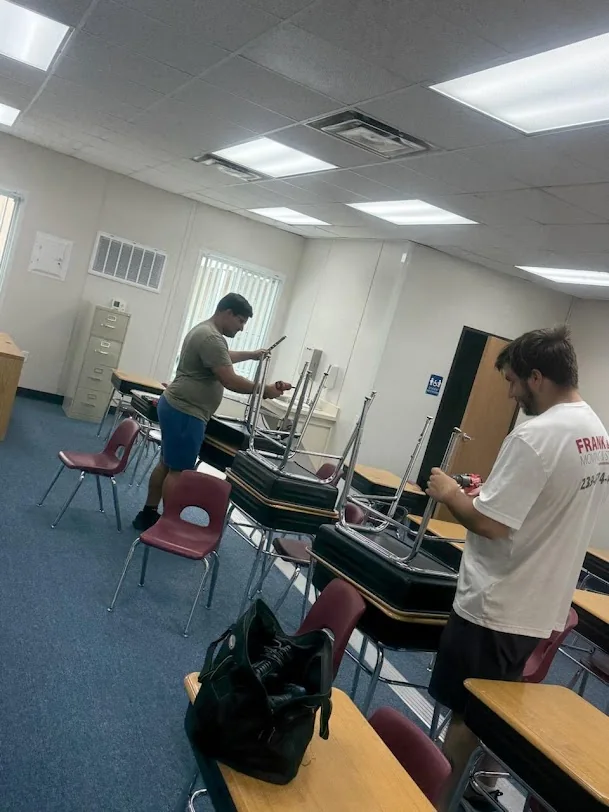 Company movers handling tables inside a room