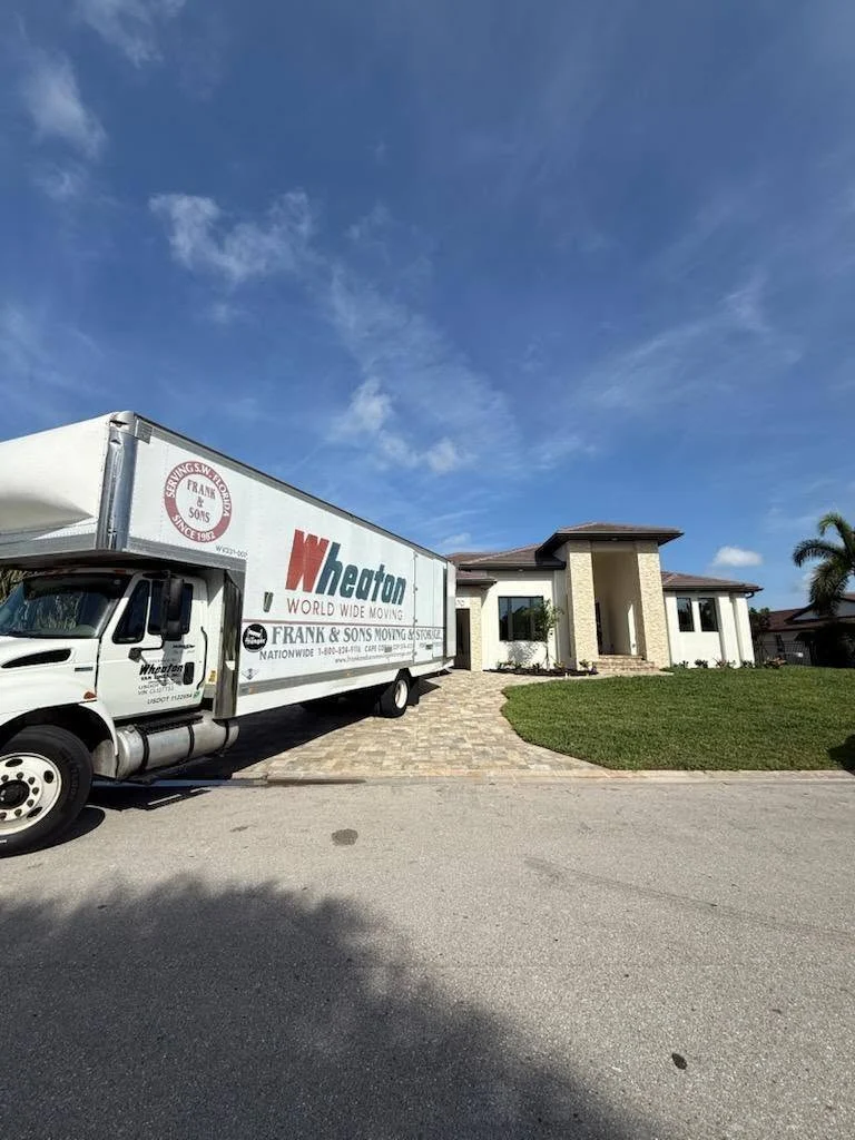 Frank and Sons moving truck outside a modern home with a stone entrance