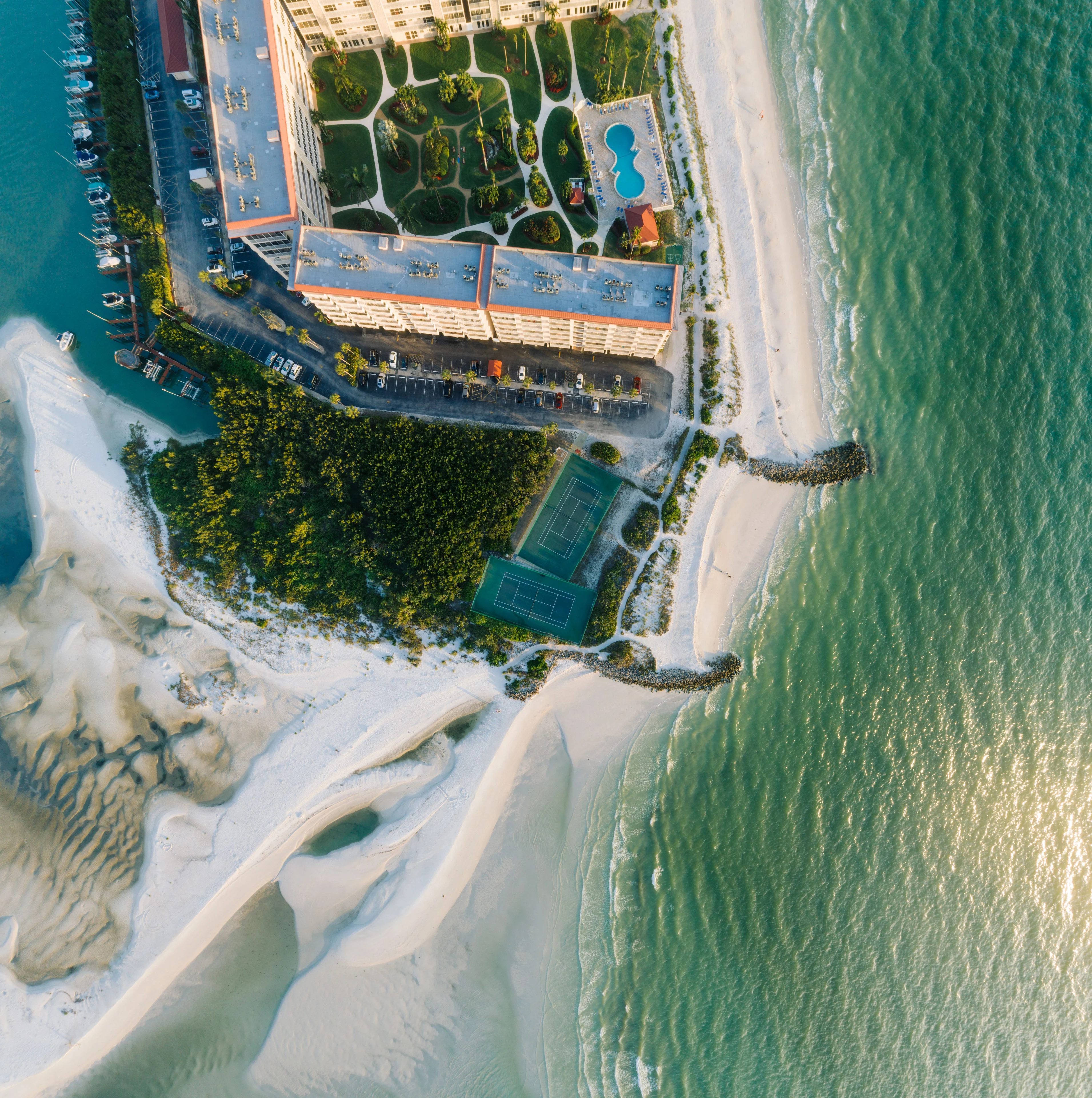 Aerial view of beachfront residences, a swimming pool and tennis courts on Marco Island