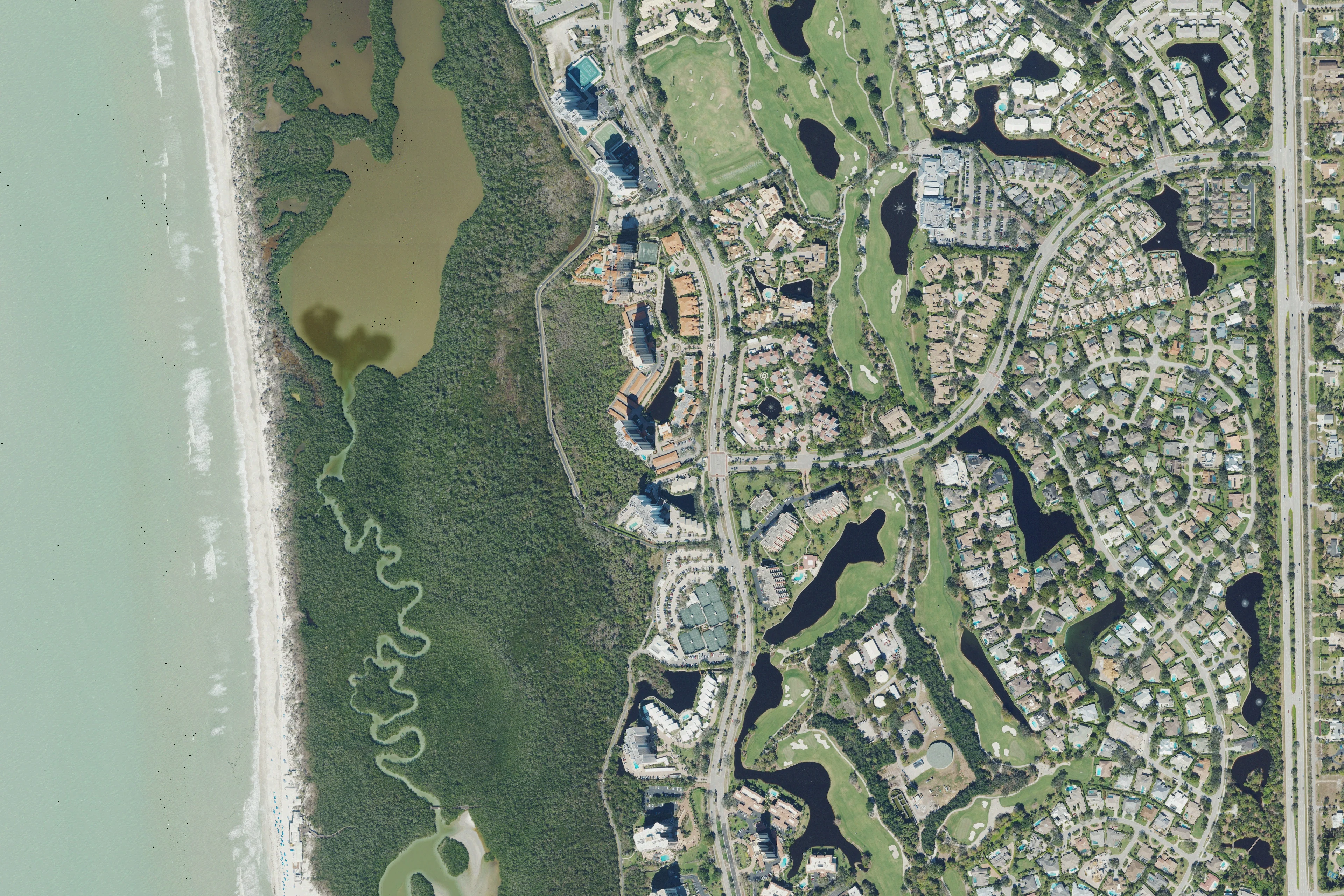 Aerial view of Pelican Bay homes, golf fairways and the coastal preserve