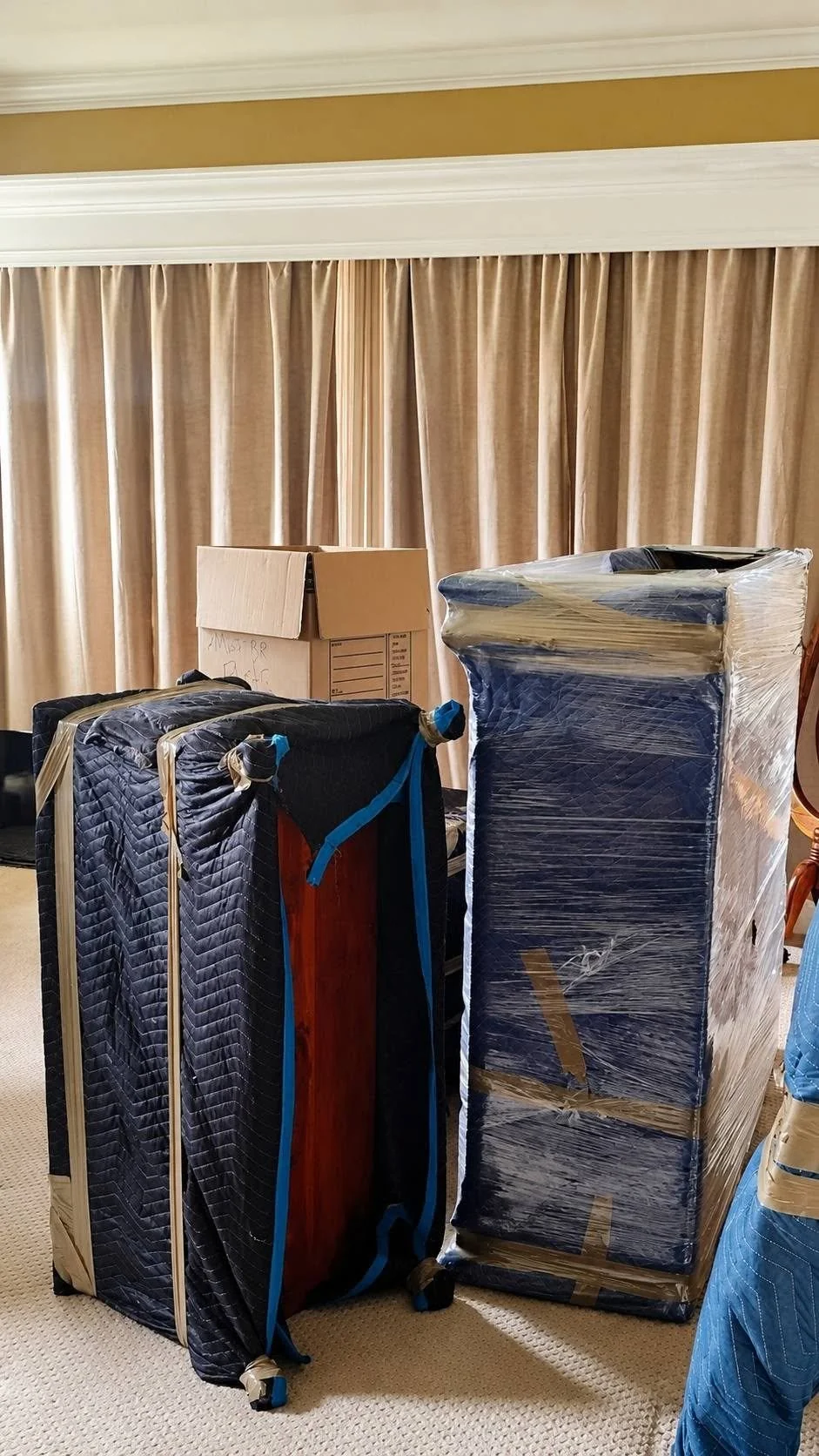 Furniture protected with blue moving blankets and clear stretch wrap