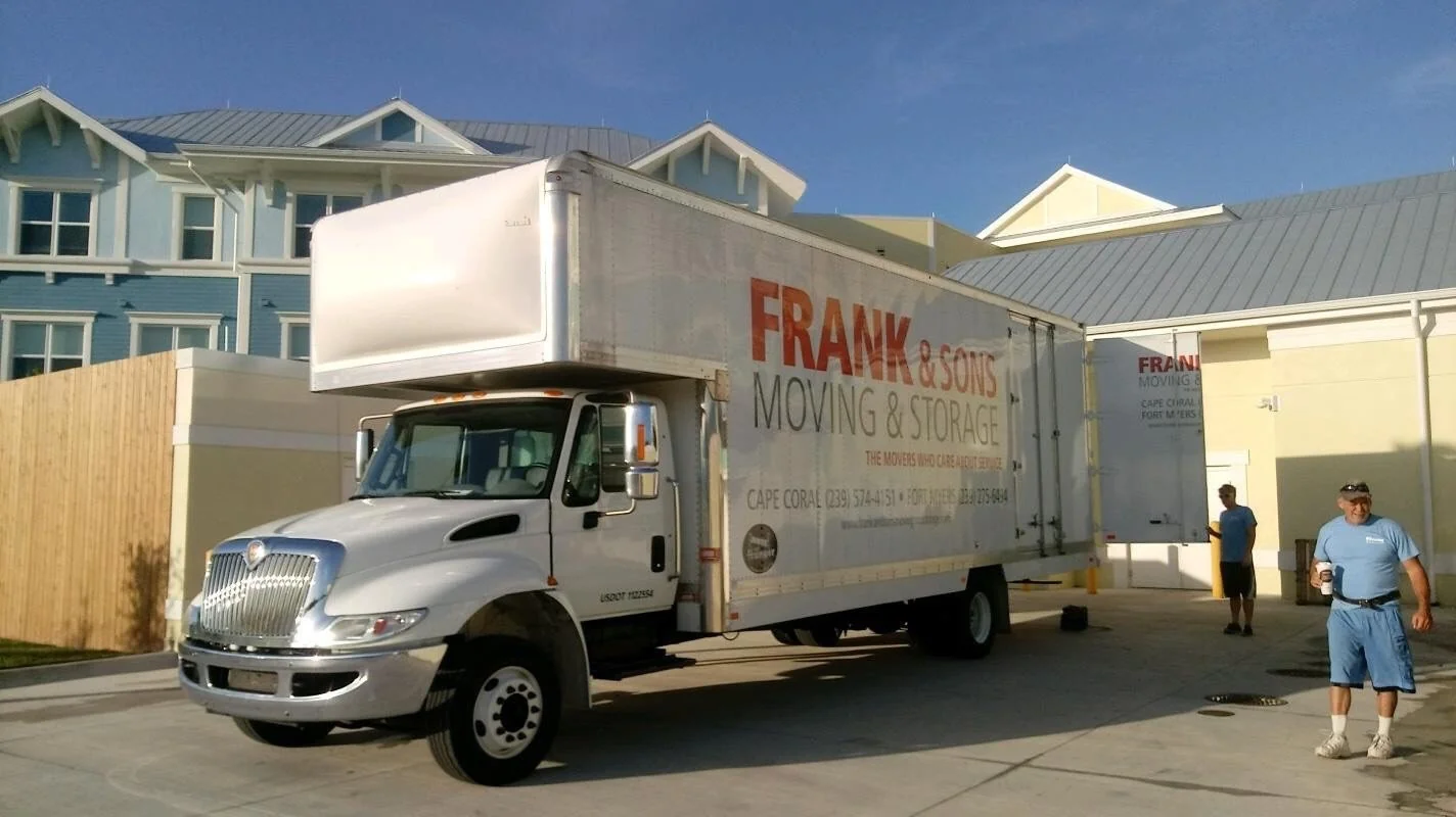 Frank and Sons moving truck and two people outside a residential garage